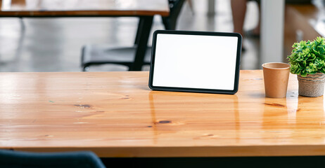 Close-up view of comfortable workplace with mock up digital tablet and tree pot on wooden table.