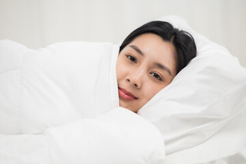 Beautiful asian woman lying in the bed . Young woman sleeping well in comfortable cozy fresh bed on soft pillow white linen. Morning in the bedroom. Health and rest concept.