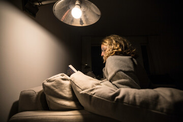 Fototapeta premium Stockholm, Sweden A woman reads a book at home on the couch.