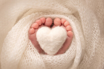 The tiny foot of a newborn baby. Soft feet of a new born in a white wool blanket. Close up of toes,...