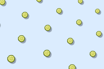 Colorful pattern of fresh cucumbers slices on blue background with shadows. Top view. Flat lay. Pop...