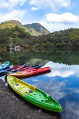 Colorful boats on the shore of a lake with the reflection of sky and hills 