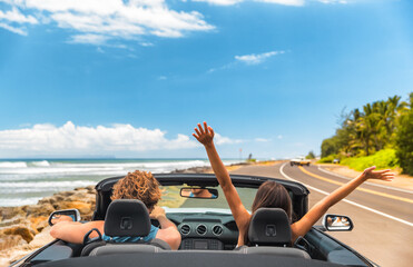 Road trip car holiday happy couple driving convertible car on summer travel Hawaii vacation. Woman with arms up having fun, young man driver - obrazy, fototapety, plakaty