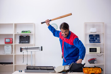 Young male repairman repairing air-conditioner