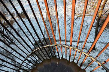 rusty sheet metal railing of individual strips at the top freely in space. spiral staircase with bars and full sheets of low fence in the city garden near the cafe in the park. sunny winter day