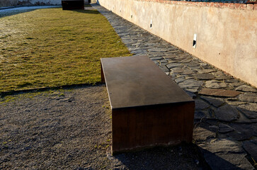 a bench of one piece of sheet metal in a regular garden with a stone walkway of gray flat slate....