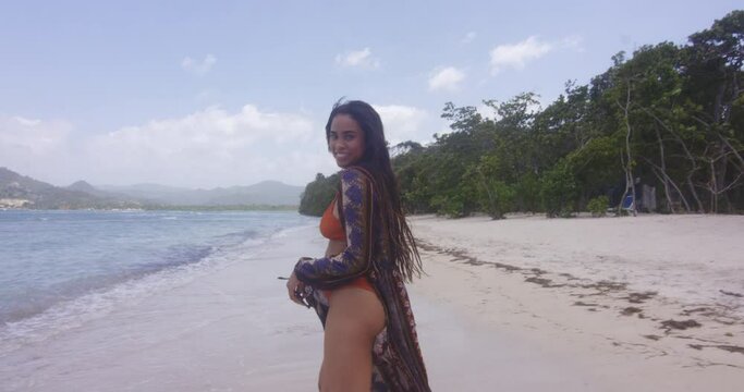 Smiling Carefree Latino Dominican Girl Model Walks on Playa Teco Maimon Tropical Beach Shore as Sea Breeze Blows, Handheld Shot