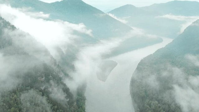 Flight over misty river. forest below, gloom after rain, fog and clouds, mountain rocks. Abakan river in the mountains of Khakassia
