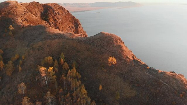Climbing over the tops of the cliffs in the rays of the evening sun, a view from a height of the bay and mountains on the shore. Evening light and silence. Tepsey Khakassia Potroshilovo. Tepsei
