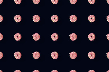 Colorful pattern of pink glazed donuts isolated on black background. Doughnuts. Top view. Flat lay