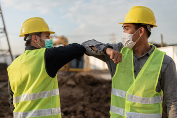 Engineers man wearing face mask and touching with elbow in building site. Construction manager and engineer man wearing face mask have a greeting by touching the elbow