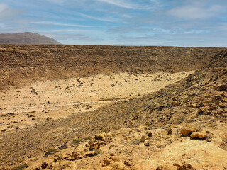 Bright sky over a rocky desert. Rough surface in a valley, dry arid African climate, hot weather in Cape Verde. Selective focus on the details, blurred background.