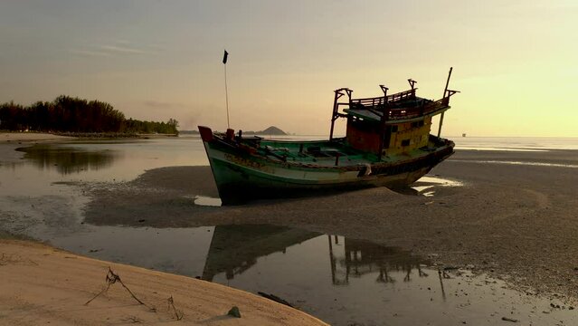 Passing old fisher boat wreck stranded on sandy shore - Sunset scenes of boat wreck along shore side - Nathon harbour - Koh Samu Island in Thailand