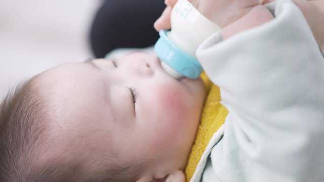 寝ながらミルクを飲むアジア人の赤ちゃん