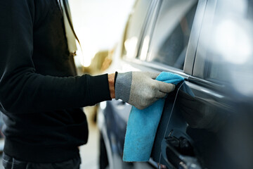 Close up of male car service worker applying nano coating on a car