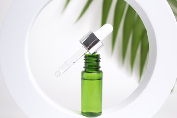 Glass dropper bottle on white background with leaves. Cosmetic container mock-ups. Background for branding and packaging presentation. Natural skincare beauty product concept