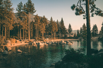 Sunset rays hitting the tall trees and turquoise water in Sand Harbor Beach in Lake Tahoe, Nevada