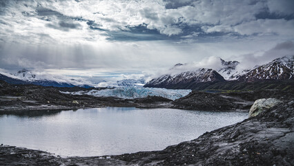 Fototapeta na wymiar Sun rays peeking through the clouds over panoramic view of mountains and lakes in Matanuska Glacier, Alaska