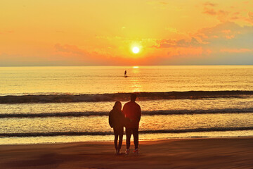 片瀬西浜海岸で沈む夕日を眺めるカップル