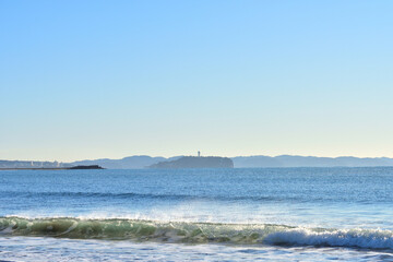 Fototapeta na wymiar 江の島を望む茅ヶ崎海岸とビーチに打ちあがる白波