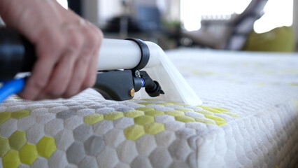 Male Worker Cleaning a mattress With Vacuum Cleaner.Professionally extraction method. Upholstered...