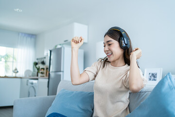 Asian girl listen to music and dance while sit on sofa in living room. 
