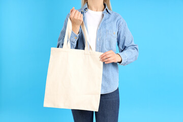 Woman holds white eco bag on blue background