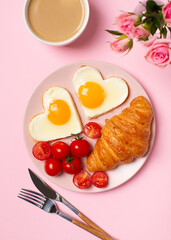 Healthy breakfast with eggs hearts and cup of coffee on pink background