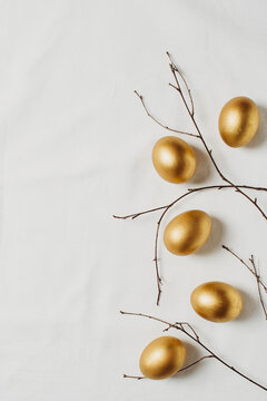 Happy easter concept flat lay with gold eggs and feather on white background