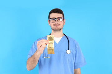 Intern doctor holding condoms on blue background