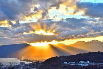 夕陽が山並みにオレンジ色の光を放射する景色