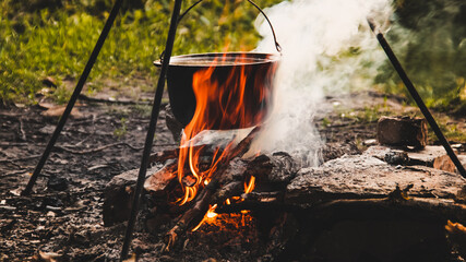 Cooking on an open fire in the field. A camp pot on a campfire close-up on a summer, clear day. Pot...
