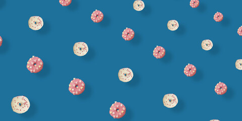 Colorful pattern of white and pink glazed donuts isolated on blue background with shadows. Doughnuts. Top view. Flat lay