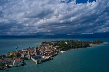 Fototapeta na wymiar Rocca Scaligera Castle in Sirmione. Aerial view on Sirmione sul Garda. Italy, Lombardy. Panoramic view at high altitude. Cumulus clouds over the island of Sirmione. Aerial photography with drone.