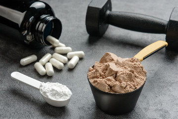 Chocolate flavored protein, creatine and amino acid capsules close-up. The concept of sports supplements.