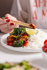 Eating dinner with teriyaki chicken with vegetables and rice