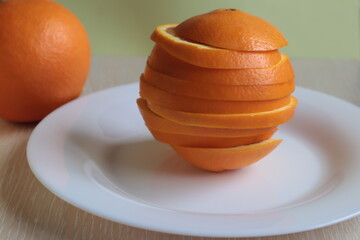 Cut the orange into circles on a white plate on the table.