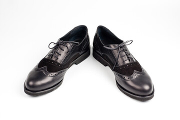 Black imitation leather shoes laced with wide laces. Close-up shot.