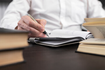 Man hands taking notes in planner. Man sitting at desk at home or in office and studying, searching and analyzing information in books or codes. Learning and business education concept. Photo