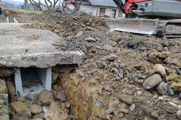 The excavator puts concrete slabs for moving through the gutter, construction work with an excavator.