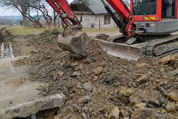 Fototapeta premium The excavator puts concrete slabs for moving through the gutter, construction work with an excavator.