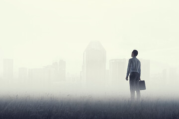 Back view of young businessman while standing with mist background