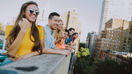 Young happy people having a barbecue dinner on a rooftop in New York.  Group of friends having party and having fun - obrazy, fototapety, plakaty