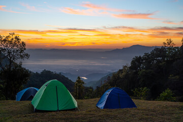 Vivid tents with awesome view to high mountain range under first light of sun in sunrise sky. Scenic landscape with tent at very high altitude with view to large mountains.