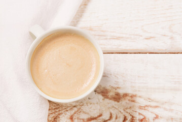 White cup of the coffee and vintage cloth
on light rustic wooden background