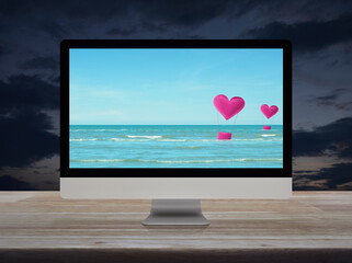 Pink fabric heart love air balloon on tropical sea with blue sky on desktop modern computer monitor screen on wooden table over sunset sky, Business internet dating online, Valentines day concept