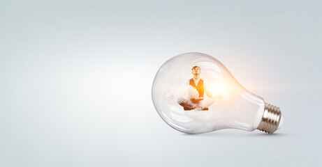 Businessman doing yoga in lotus pose inside light bulb