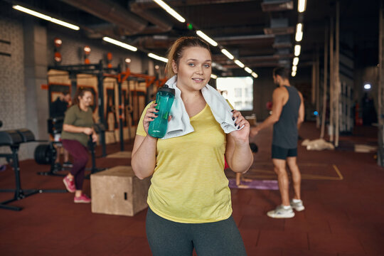 Girl looking at camera and drinking water in gym