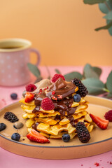 Waffle with with banana ice cream and chocolate. Delicious belgian waffles with berries on pink background. Coffee and dessert. Sweet food.
