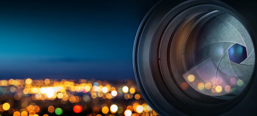 he camera lens on the background of the fiery city lights. Concept on the topic of news, media,...